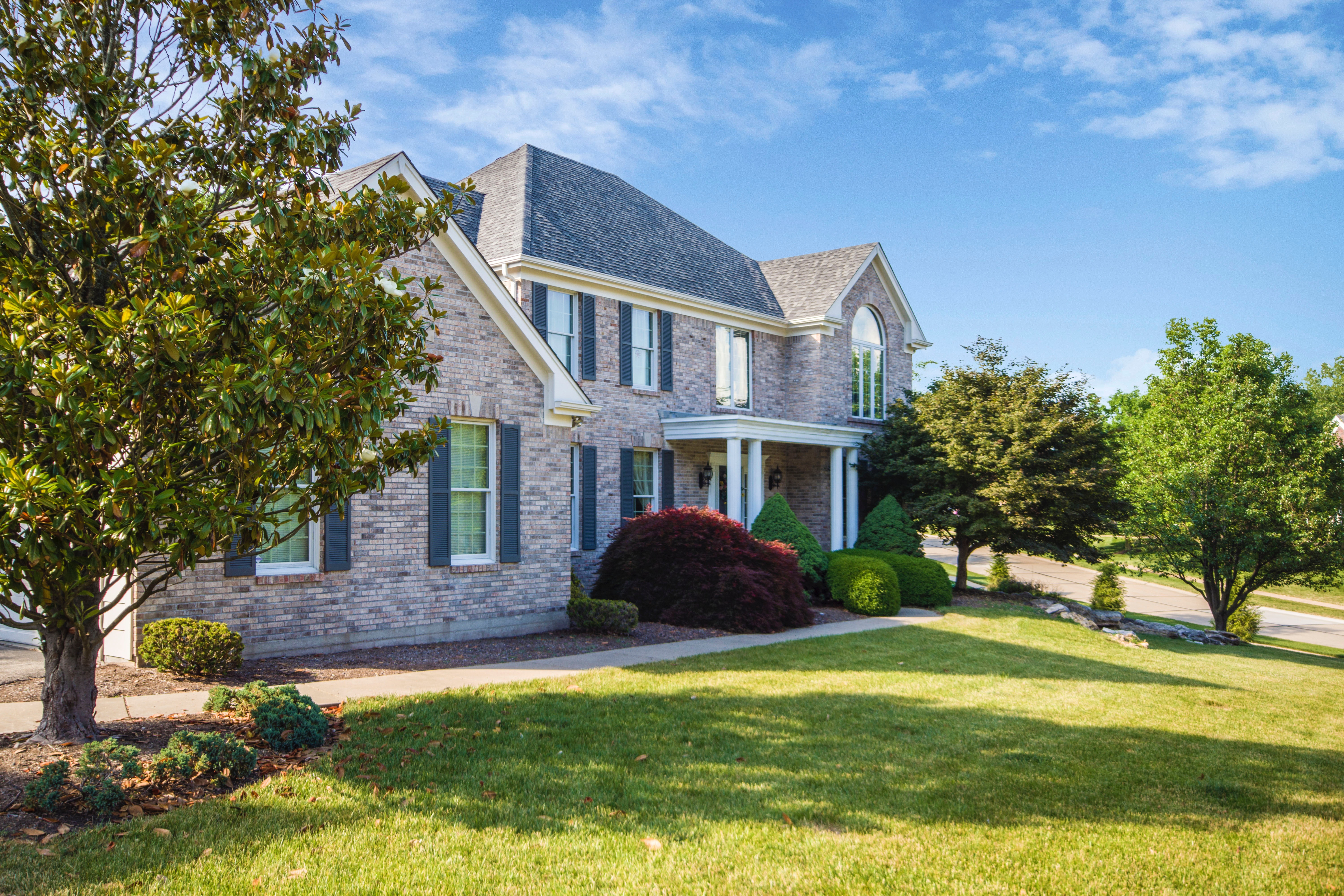 Grey stone house with a manicured, weekly serviced lawn